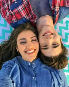 two people laying on top of each other with their faces close to one another and smiling at the camera