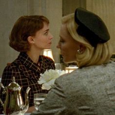 two women sitting at a table talking to each other