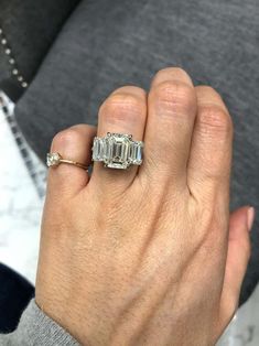 a woman's hand holding an engagement ring with three baguettes on it