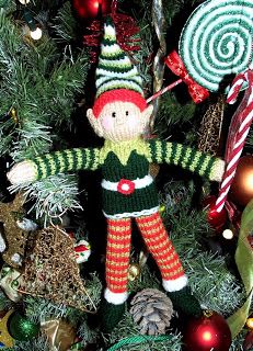 a knitted elf ornament hanging from a christmas tree with candy canes