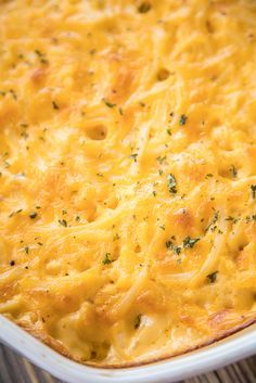 a cheesy casserole in a white dish on top of a wooden table