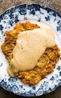 chicken fried steak with gravy on a blue and white plate