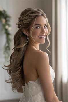 a woman with long hair wearing a wedding dress and smiling at the camera while standing in front of a window