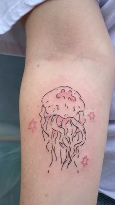 a small jellyfish tattoo on the right arm and shoulder, with stars around it