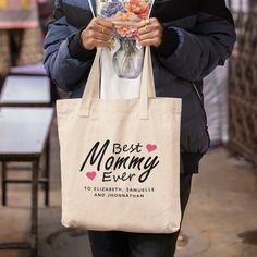 a woman holding a tote bag with the words best mommy ever printed on it