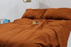 the bed is made with brown linens and has a book on top of it