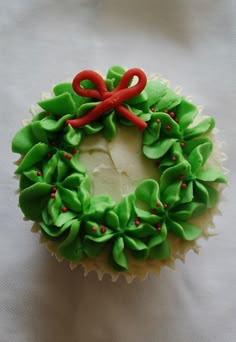 a cupcake decorated with green icing and red bows on it's side