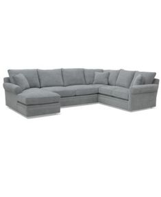 a gray sectional couch with pillows on it's back and the seat facing outward