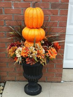 a large pumpkin sitting on top of a planter filled with flowers