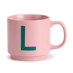 a pink coffee mug with the letter l on it's side and a green handle