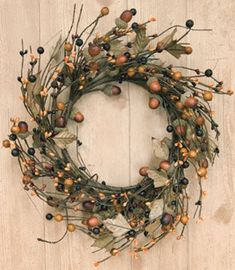 a wreath hanging on the side of a wooden wall with leaves and acorns