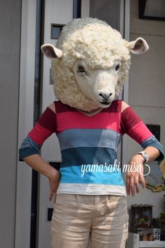 a woman wearing a sheep mask standing in front of a door with her hands on her hips