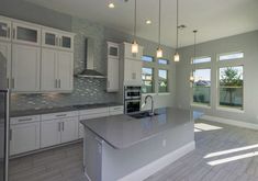 a large kitchen with white cabinets and stainless steel appliances, along with an island in the middle