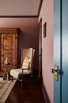 a room with a chair, rug and wooden cabinet