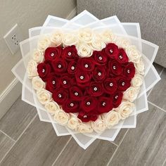 a heart shaped box filled with red and white roses