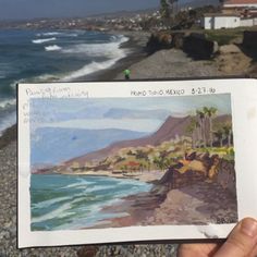 a person holding up a piece of paper near the ocean