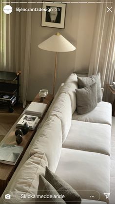 a living room filled with white couches next to a lamp and window sill