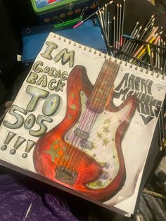 a drawing of an electric guitar on top of a spiral notebook with pencils next to it