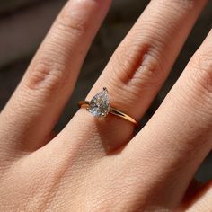 a woman's hand with a diamond ring on top of her finger, showing the center stone