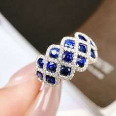 a woman's hand holding a ring with blue and white stones