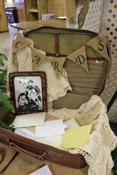 an open suitcase sitting on top of a floor next to a table with pictures and papers