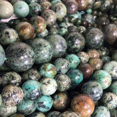 many different colored beads are stacked on top of each other in this pile, one is green and the other has brown speckles