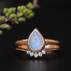 a close up of a ring with a rainbow colored stone in the middle and three diamonds on each side