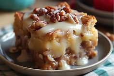 a slice of pecan pie on a plate with white icing and nuts around it