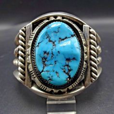 "VINTAGE NAVAJO BRACELET DESCRIPTION: This extraordinary cuff features a huge and gorgeous specimen of Sleeping Beauty turquoise. The gemstone is secure in picket fence bezel, on a foundation of heavy gauge vintage sterling silver. Thick twisted silver wire decorates the interior and sides of the cuff. This bracelet will be a cherished addition to your collection of fine vintage Native American jewelry. MEASUREMENTS: Interior of the cuff measures 5\" with an additional 1 1/2\" non-adjustable gap Classic Handmade Cuff Bracelet Collectible, Vintage Blue Cuff Bracelet, Vintage Collectible Bangle Cuff Bracelet, Vintage Collectible Cuff Bangle Bracelet, Vintage Heavy Bangle For Gift, Vintage Cuff Bracelets For Collectors, Vintage Cuff Bracelets Collectible, Collectible Vintage Cuff Bracelet, Navajo Silver Jewelry