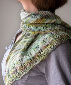 a woman wearing a knitted shawl in green and multicolored yarns