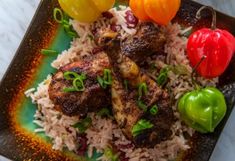 a plate with rice, meat and vegetables on it next to some chilies or peppers