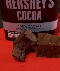 two pieces of chocolate next to a bottle of hershey's cocoa on a red cloth