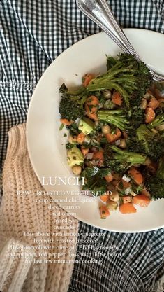 a white plate topped with broccoli and carrots on top of a table