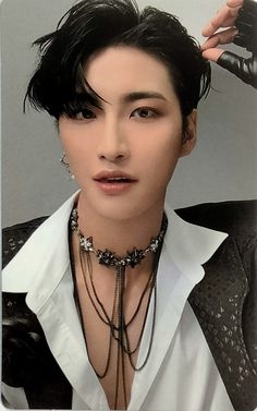 a man with black hair wearing a white shirt and silver necklaces on his neck