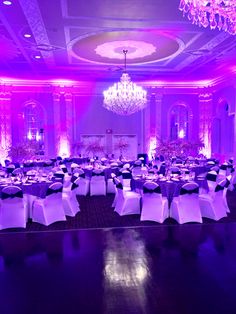 a banquet room set up for a formal function with purple lighting and chandeliers