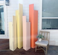 four tall, multicolored panels sitting on top of a wooden floor next to a chair