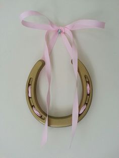 a pink ribbon is tied around a wooden toy horse ring on a white table top