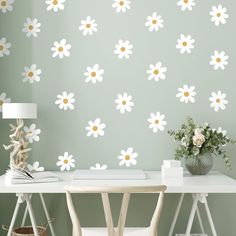 a white desk topped with a lamp next to a wall covered in flower decals