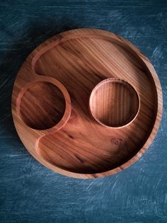 two wooden bowls sitting on top of a blue surface