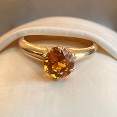 a yellow diamond ring sitting on top of a white cloth covered cushioned seat pad