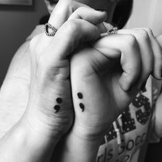 two people with matching tattoos on their wrist and one is holding the other's hand