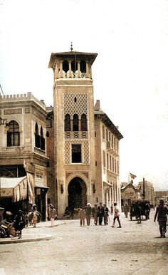 an old photo of people walking around in front of a building with a clock tower