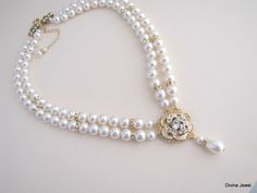 "This romantic double strand necklace has a victorian style rose pendant with clear stones set on an antique gold filigree. I have used Swarovski pearls in ivory/cream. All the Swarovski crystals in the pendant are handset by me. Pearls measure 8 mm in both strands accented with rhinestone beads. Rhinestone pendant is just under 1\" in diameter. Necklace is 17\" long inner strand. Finished off with antique gold finish filigree clasp adorned with Swarovski crystals. It comes with a 2\" extender c Gold Pearl Embellished Necklaces For Wedding, Gold Costume Jewelry Pearl Necklace For Wedding, Pearl White Costume Jewelry Necklaces For Wedding, Gold Pearl Bridal Necklace For Mother Of The Bride, Gold Pearl Chain Necklace For Mother Of The Bride, Mother Of The Bride Gold Pearl Bridal Necklace, Multi-strand Pearl Drop Beaded Necklaces For Weddings, Wedding Multi-strand Pearl Drop Necklaces, Wedding Pearl Necklace With Multi-strand Pearl Chain