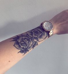 a woman's arm with a rose tattoo on it and a watch in the middle