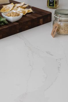 some food is sitting on a cutting board next to a glass jar and bottle with something in it