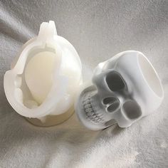 two plastic skulls sitting next to each other on a bed