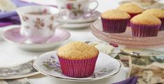 muffins on plates and teacups sitting on a table