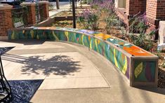 a colorful bench sitting on the side of a sidewalk