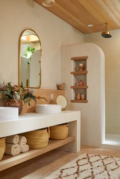 a bathroom with a sink, mirror and shelves filled with baskets on the counter top