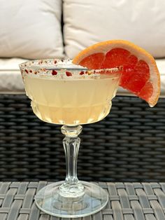 a drink sitting on top of a table next to a slice of grapefruit